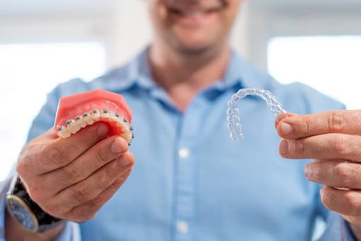 Orthodontist holding a dental model with braces and a clear aligner to explain adult orthodontic treatment age limit