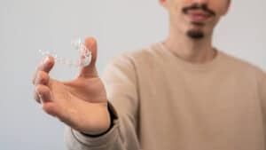 Adult holding a clear aligner tray to show adult bite correction options