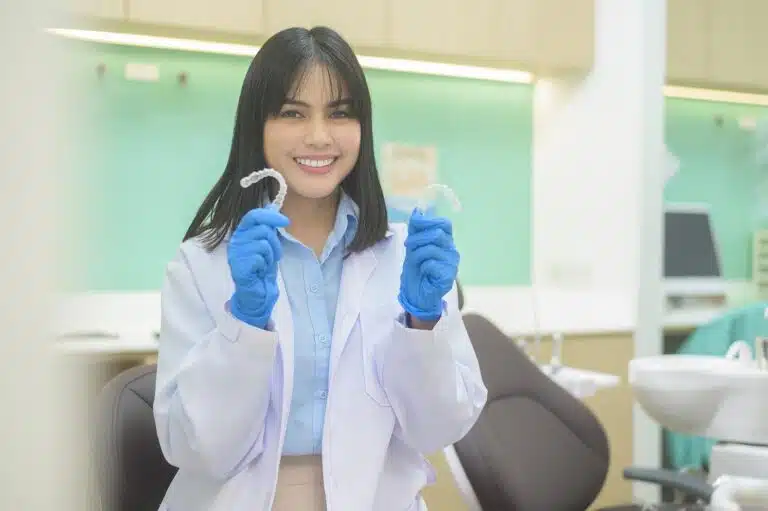 Female dentist in a dental office holding up a pair of clear plastic aligners