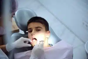 Overhead view of a young boy receiving a dental exam with a mouth mirror at a pediatric dental clinic