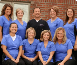 Group portrait of the Bowers Orthodontics staff smiling in blue and black scrubs